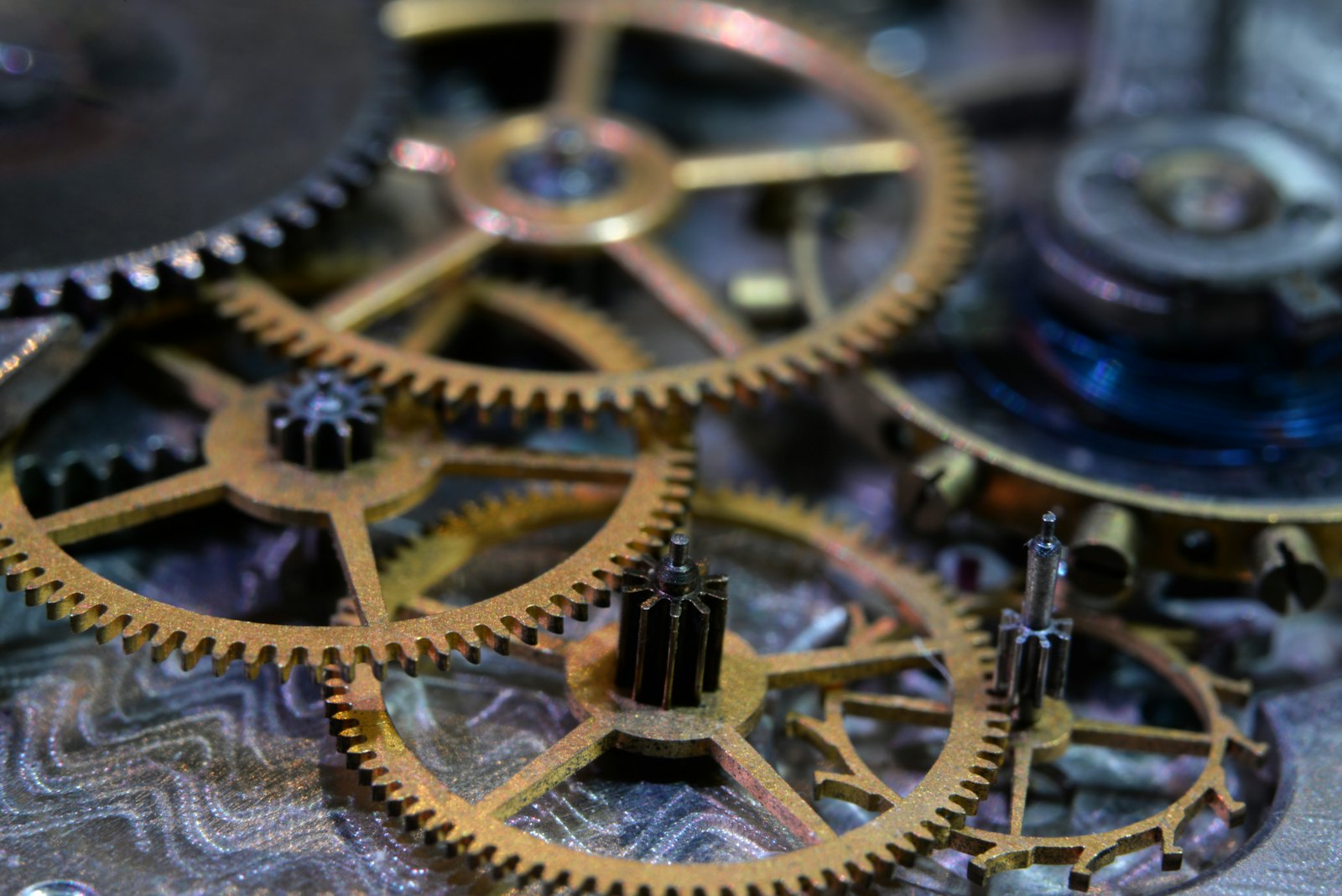 Macro photograph of interlocking brass clockwork gears resting on a circuit board — a mechanism that behaves the same way every time.